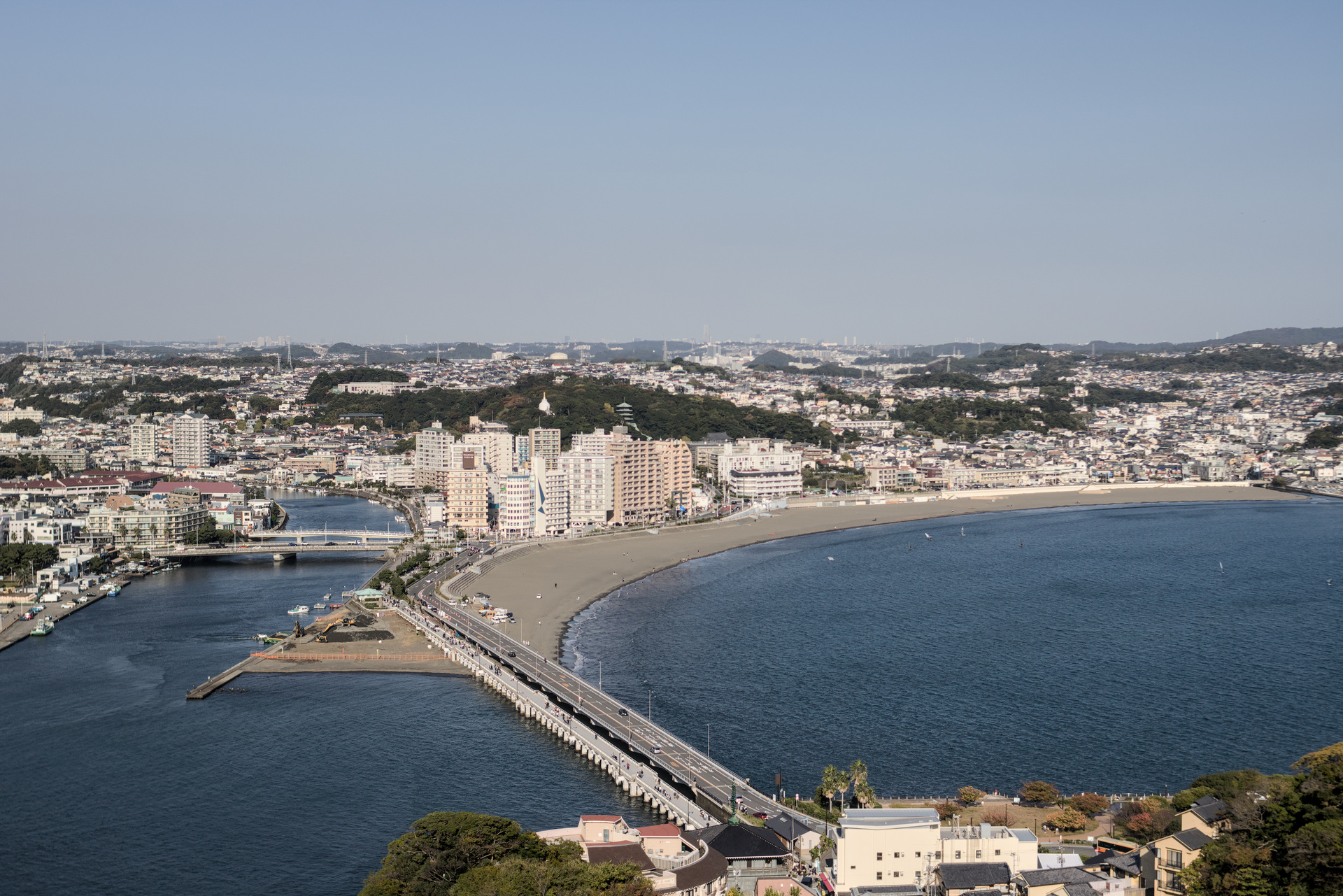 Photograph from above of urban shoreline in Japan with a bridge crossing over to an island.